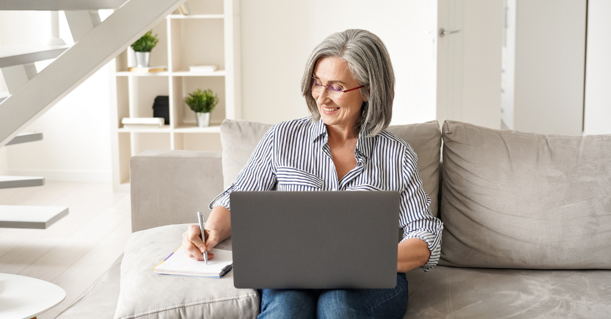 woman holding laptop and taking notes