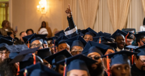 group picture of graduates in caps and one man pointing in the air