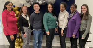 Image description. Seven members of the JEVS Human Resources team stand in front of a balloon display and smile for a team photo.